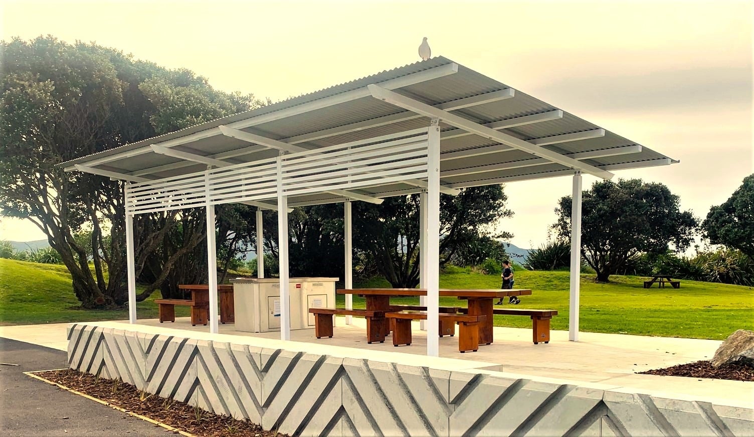 Solid timber picnic tables and seats beneath a park shelter